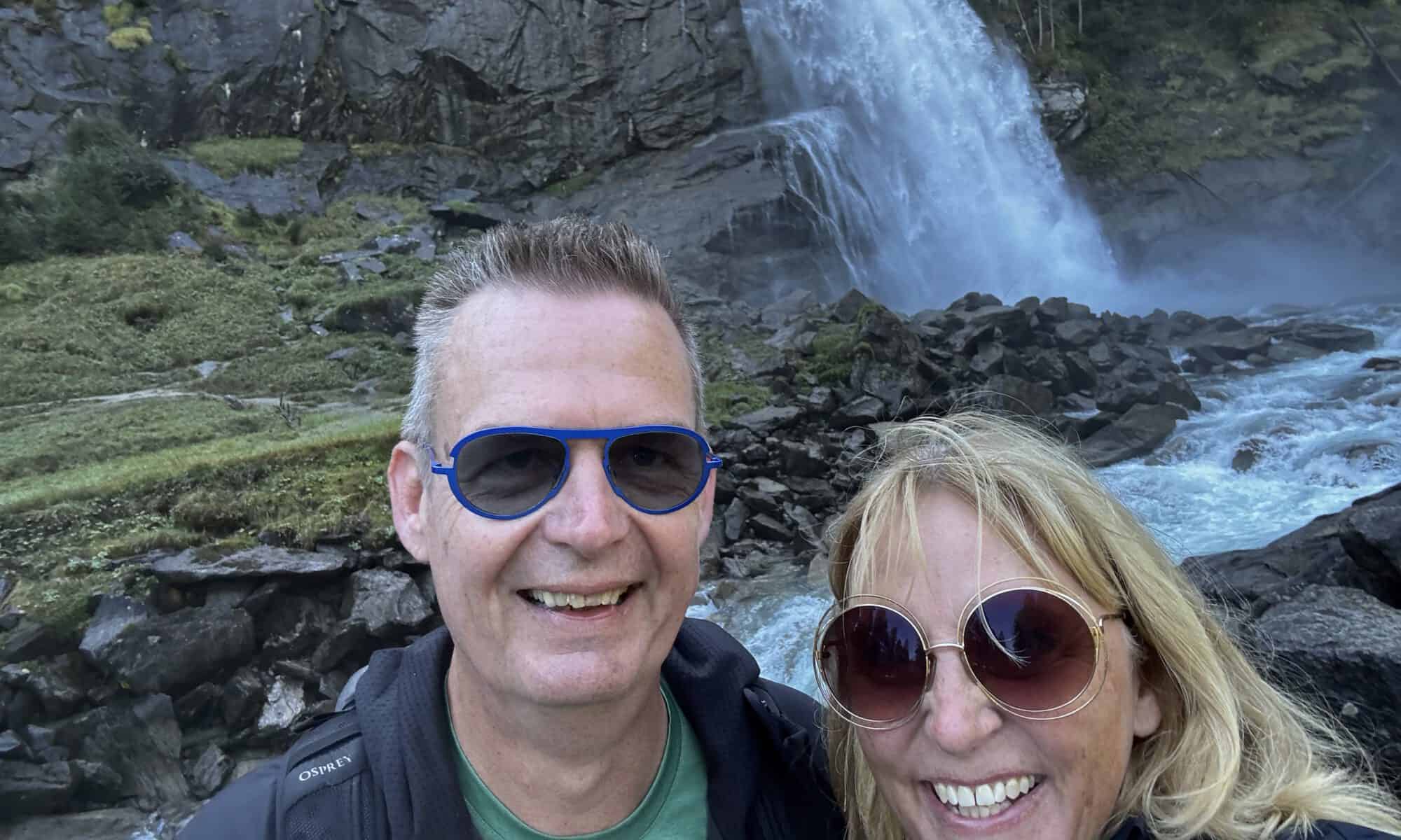 Fotocaptie: Blije toeristen genieten van de natuurlijke waterval en serene omgeving.